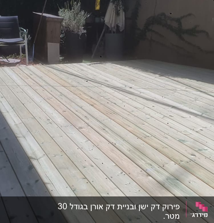 דק עץ רחב עם כיסא וצמחייה ברקע